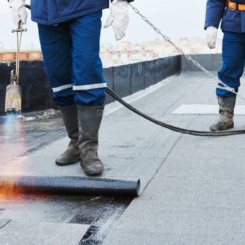 Twee professionals brengen een beschermende dakcoating aan om de dakpannen te beschermen tegen vuil en weersinvloeden.