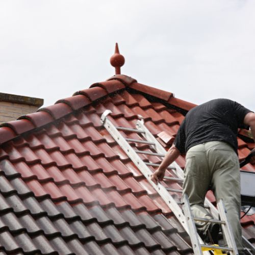 Een professional impregneert een dak om het waterafstotend en beschermd tegen mos en vuil te maken.